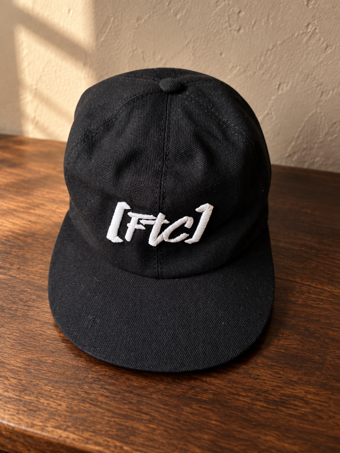 FTC Est. 2019 Cap auf dunklem Holz – inszeniertes Produktbild auf Basis des Originalfotos
