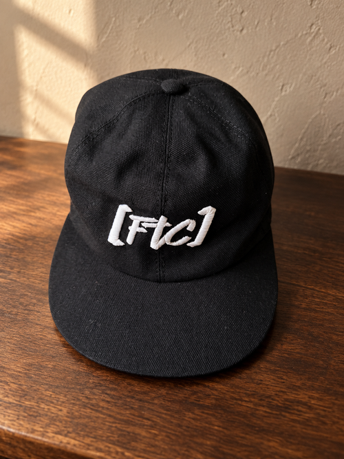 FTC Est. 2019 Cap auf dunklem Holz – inszeniertes Produktbild auf Basis des Originalfotos
